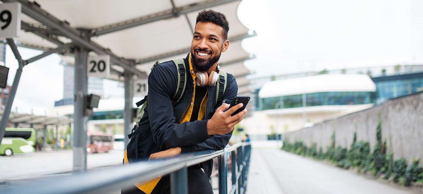 A young man holding a smartphone and looking optimistic 