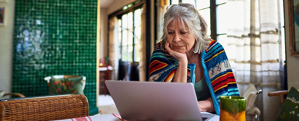 Elderly lady at home using a laptop to apply for a financial producft