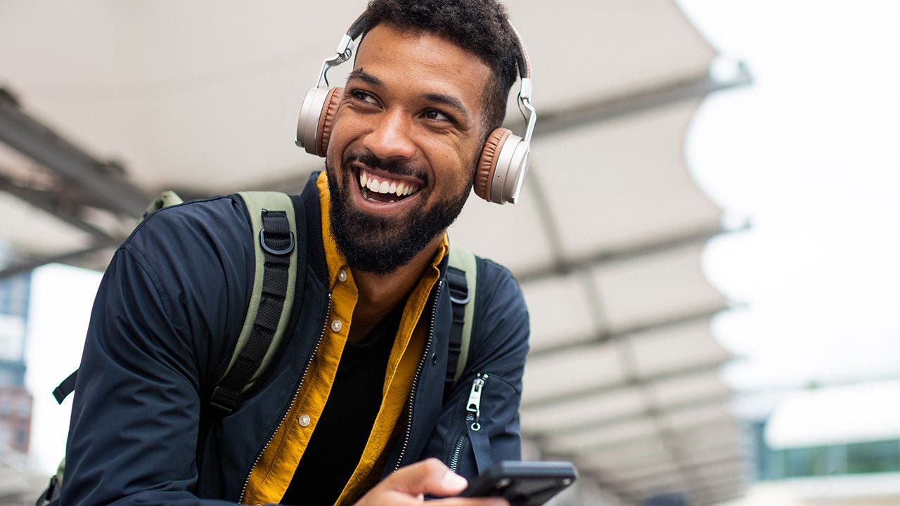 A picture of a young man smiling using a smart phone.