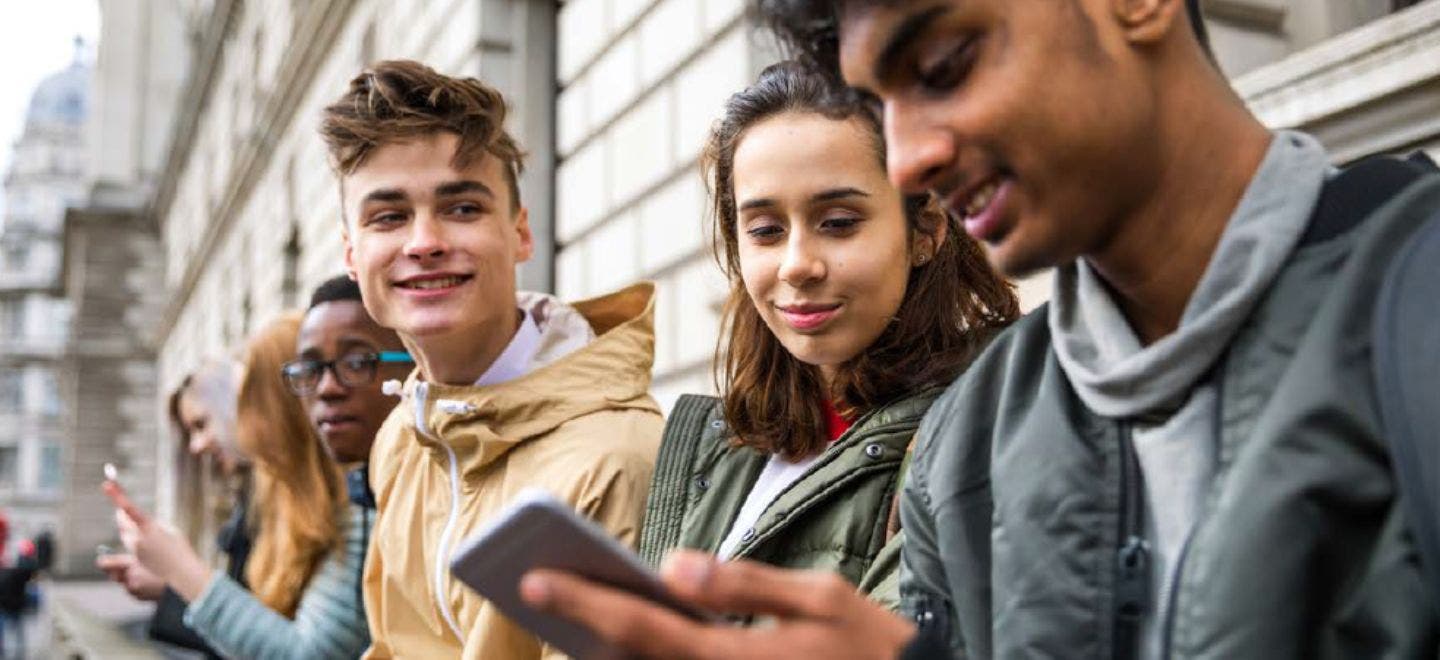 Group of Gen Z talking and looking at mobile phones