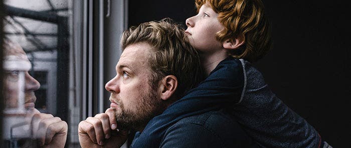 Man and son looking out a window and pondering the future