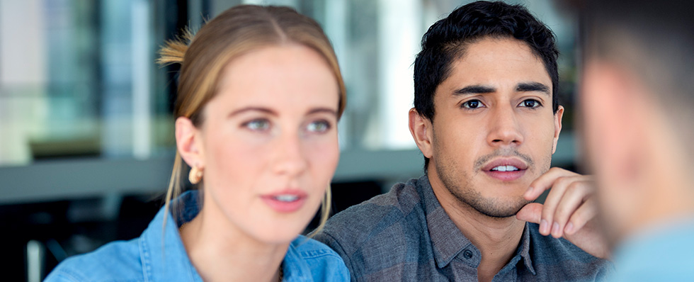 A financial advisor at a bank talks to customers about their application for a new bank account.